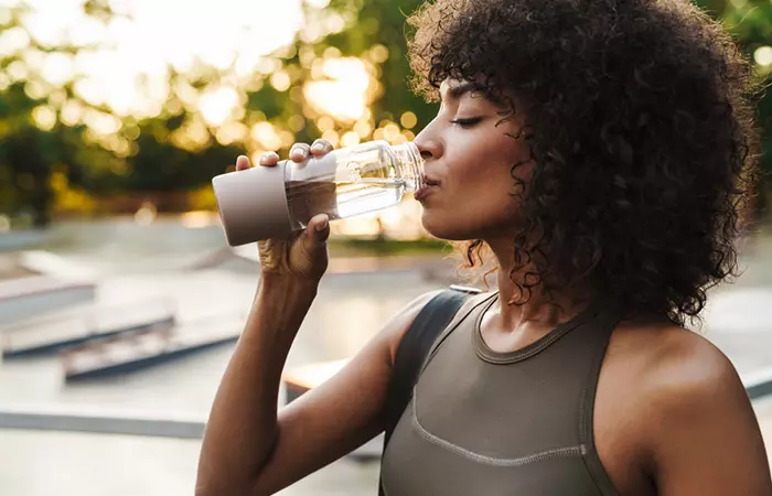 Woman drinking water to keep her 4C hair moisturized