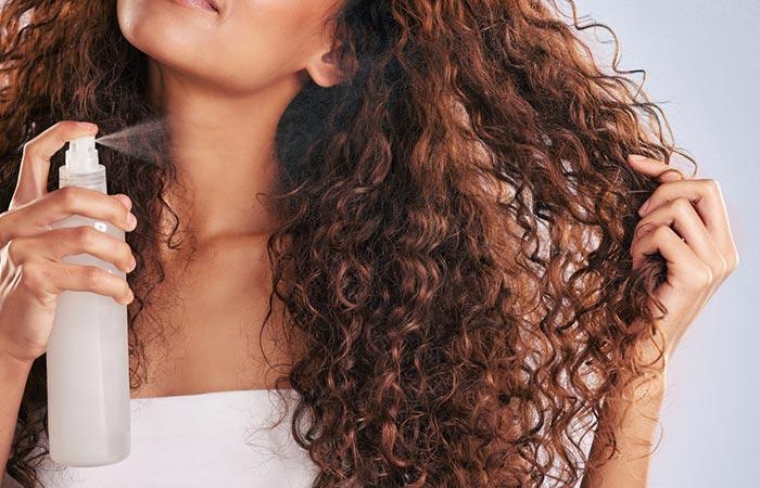 Woman applying hair spray on her hair