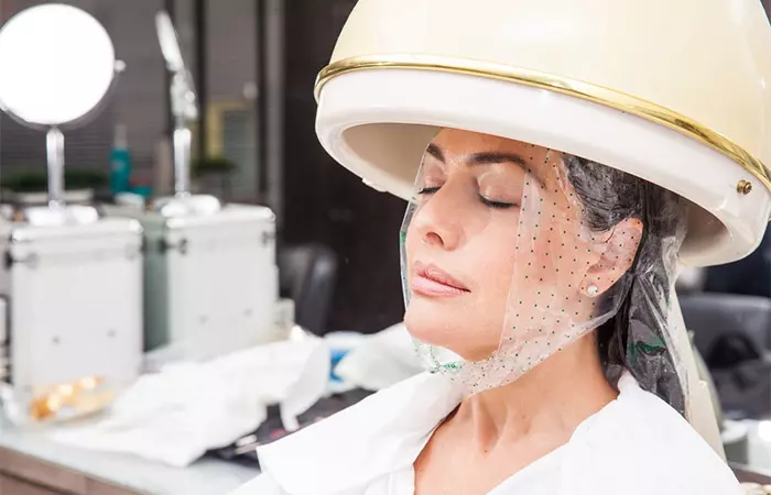 Woman undergoing treatment under a professional hair steamer