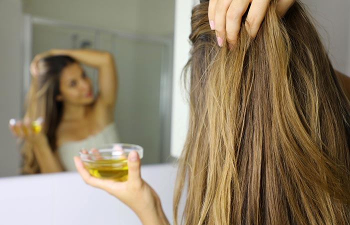 Woman applying canola oil to hair