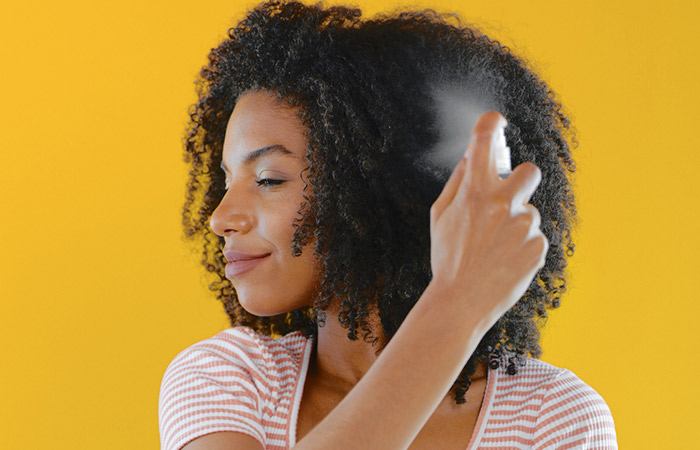 An African woman spraying water on her hair.