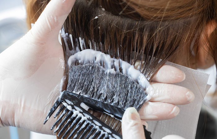 Hairdresser applying permanent hair color.