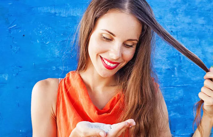 Woman applying dry shampoo on her hair before straightening it