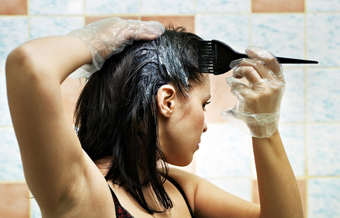 Woman applying hair dye on greasy hair