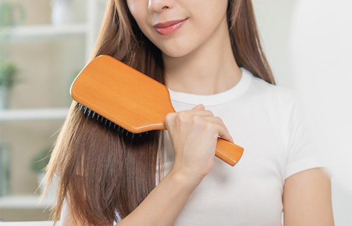 Close up of a woman brushing her hair with a paddle brush