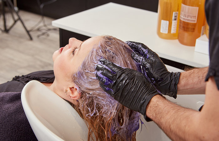 A salon professional using a toner on the client's hair