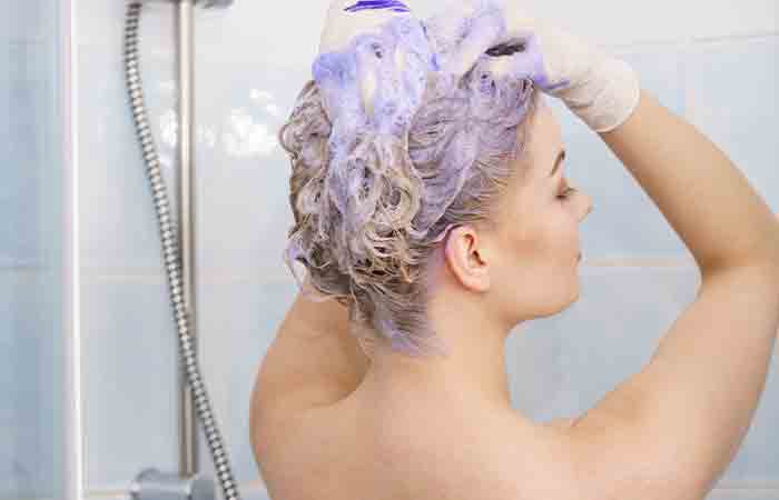 Woman removing brassy tones from brown hair with purple shampoo