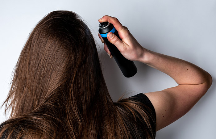 Woman applying dry shampoo to maintain the hair colour