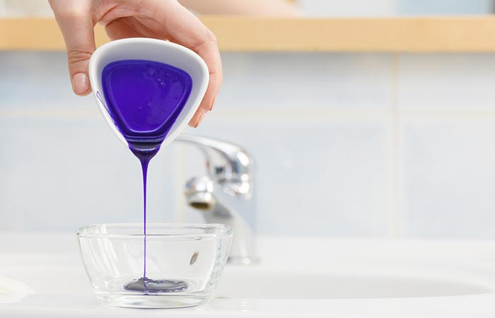 Closup of hand pouring purple shampoo in a bowl