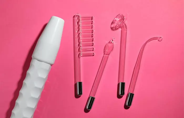 High-Frequency Hair Treatment machine with different nozzles laid flat on pink background
