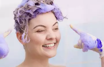 Woman using purple shampoo on her blonde hair