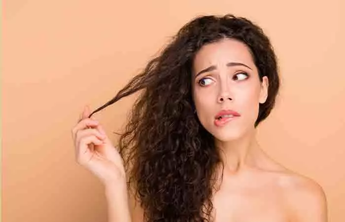 Woman worried about her dry and damaged curly hair