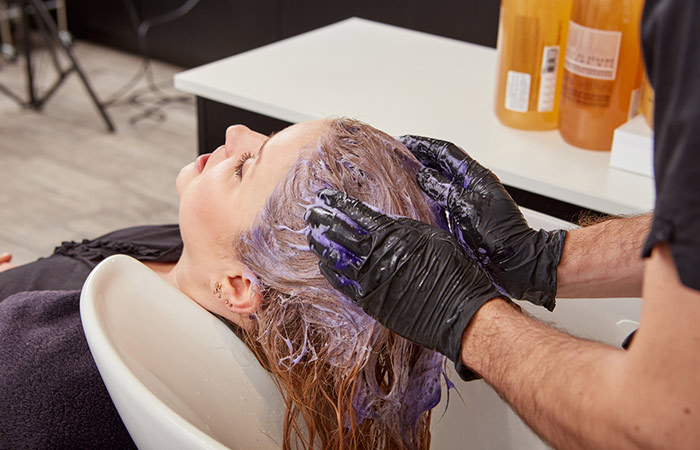 Salon expert using toner on a woman's hair to avoid brassy tones