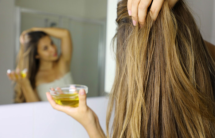 Woman applying a mixture of argan and castor oils on hair