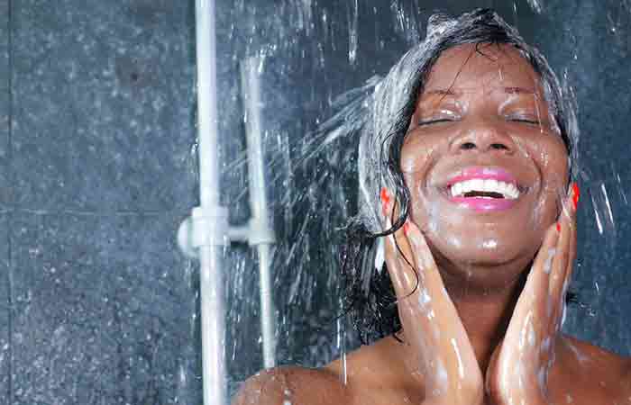 Woman washing hair with cold water to prevent dry curly hair