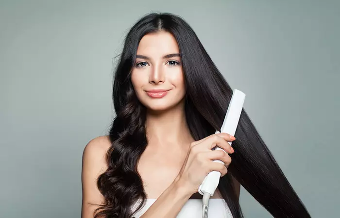 Woman straightening her curly long hair with a silk press