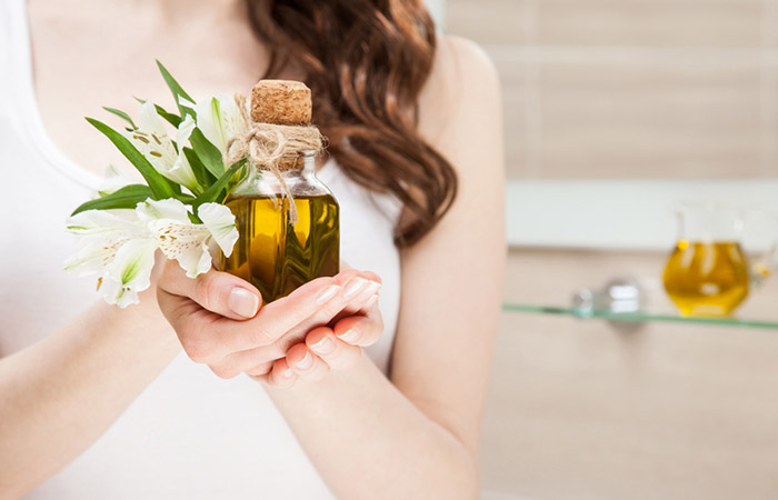 Woman holding bottle of olive oil for dry hair.