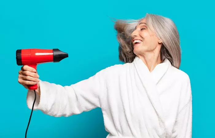 Woman drying her gray hair with ionic dryer