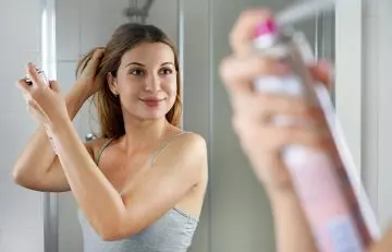 Woman using spray-on root concealers to avoid hair colour frequently
