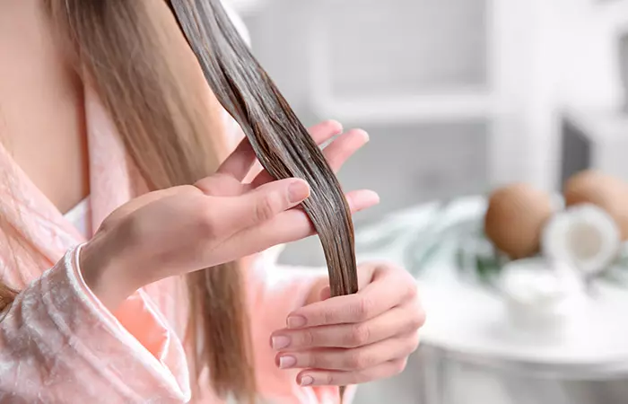 Woman follows resverse wash and applies conditioner to her hair