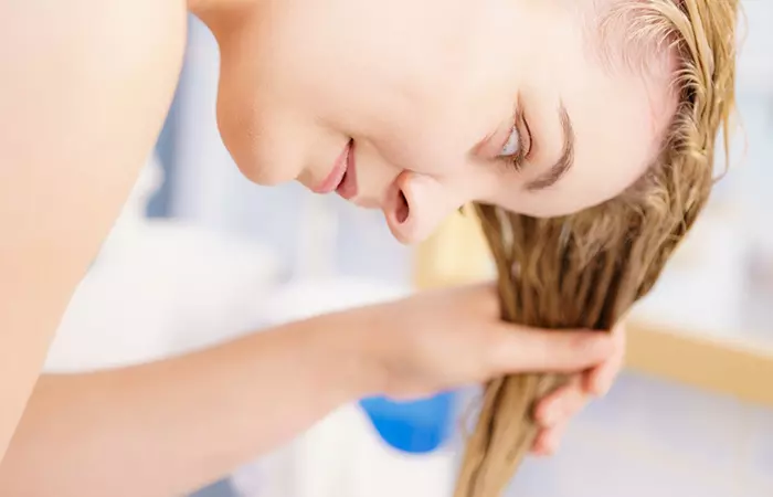 Woman squeezing out excess water from her hair before conditioning