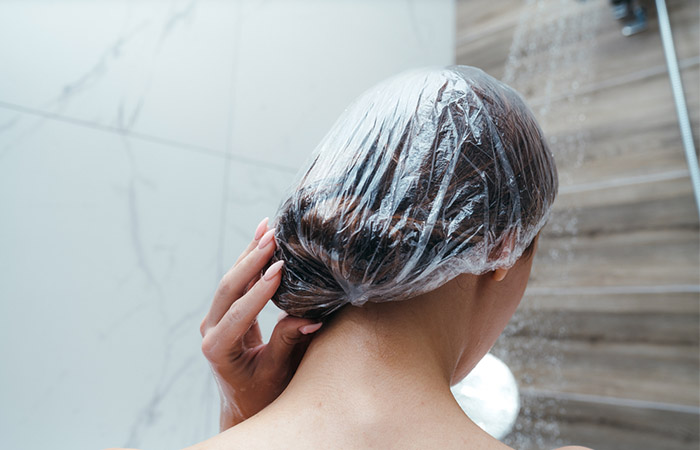 Woman taking a shower with shower cap to protect hair colour