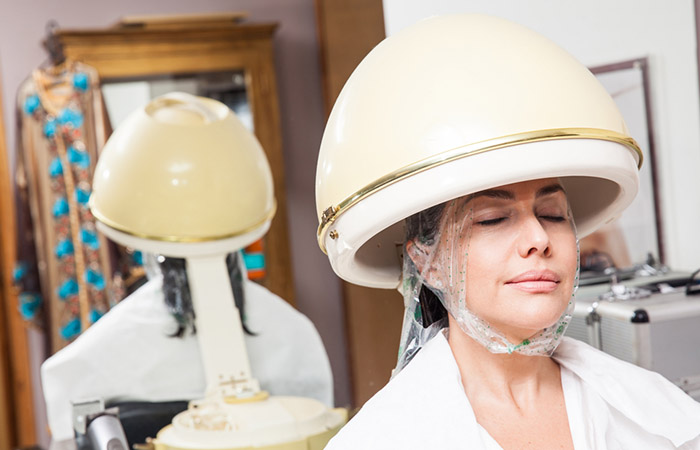 Woman using hair steamer to enhance hair moisturization.