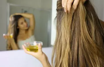 Woman applying mix of olive oil and coconut oil for good hair health