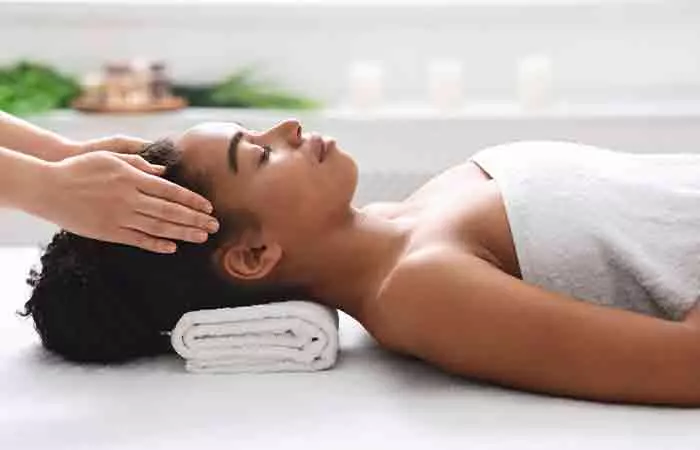 Woman getting scalp massage done to prevent dry curly hair