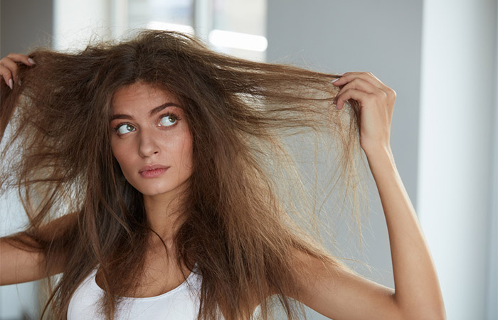 Woman looking at dry frizzy hair after frequent shampoo