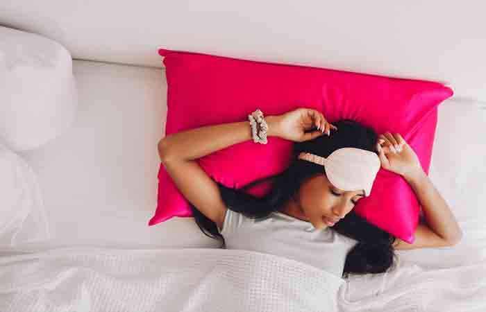 Woman sleeping on silk pillowcase to prevent dry curly hair