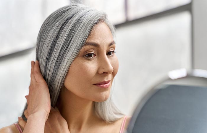 Woman softening her gray hair by applying hair cream