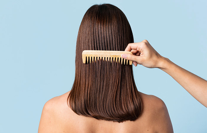 Woman combing her hair with wide toothed comb