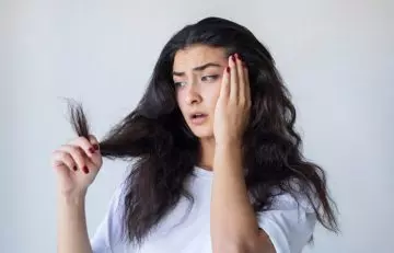 Woman looks at her dry hair