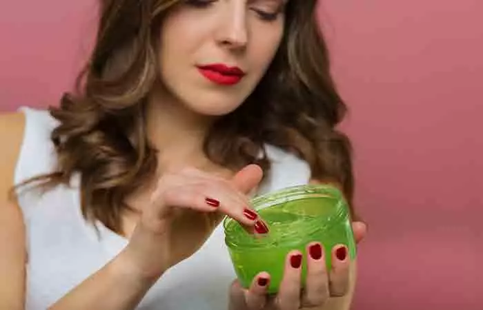 Woman applying aloe vera and shea butter gel to hair