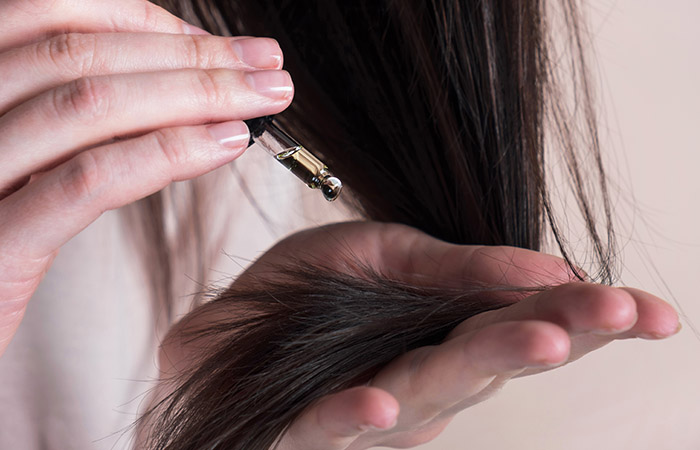 Woman applying biotin-rich oil to her hair