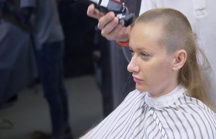 Woman shavig her head to get rid of head lice.