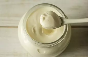 A spoonful of mayonnaise scooped out of its container