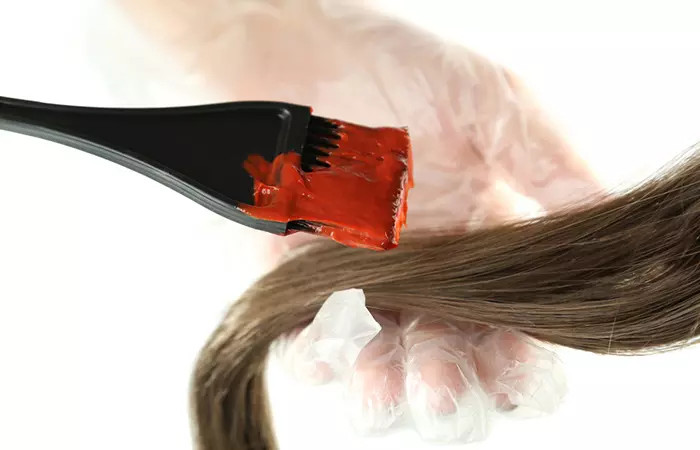 Gloved hands applying dye to the tips of the hair