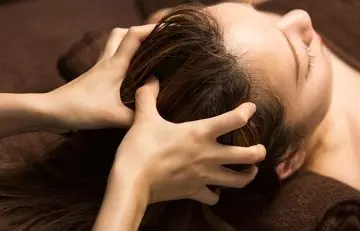 Woman gets he scalp massaged for healthy hair growth