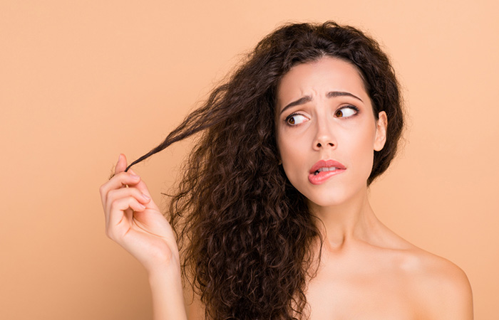 Woman looking at her heat-damaged curly hair