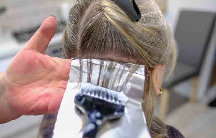 A hair specialist following steps to bleach the hair of a girl.
