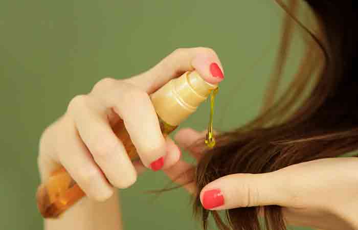 Woman applying argan oil to moisturize low porosity hair