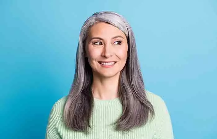 A woman with gray hair is smiling and looking away from the camera.