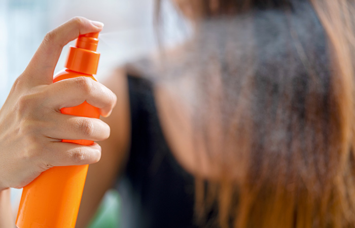 Woman spraying moisturizing conditioner on her hair