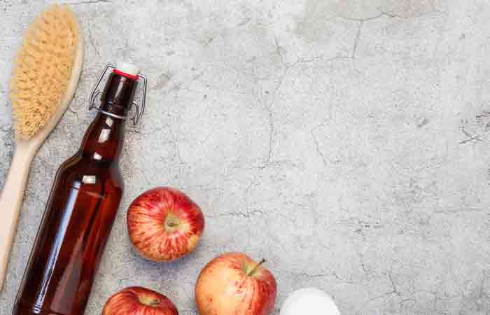 Bottle of apple cider vinegar beside a hairbrush