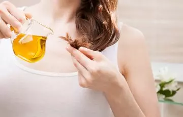 Woman applying hot oil to her hair to treat it
