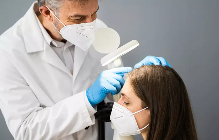 Dermatologist checking woman's scalp for dandruff