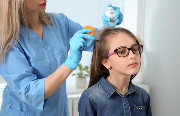 An expert performs anti-lice treatment on a girls head at her clinic