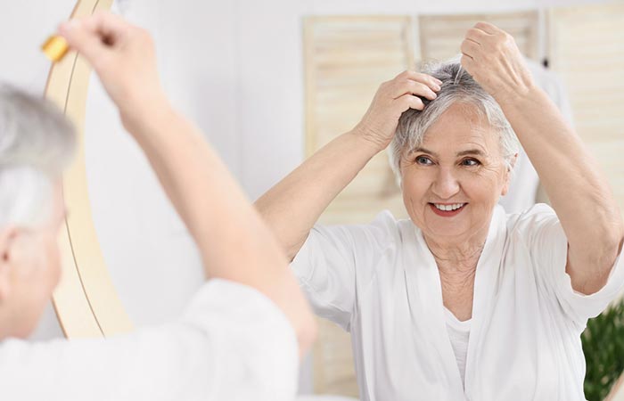 Elderly woman applying hair serum for shiny gray hair